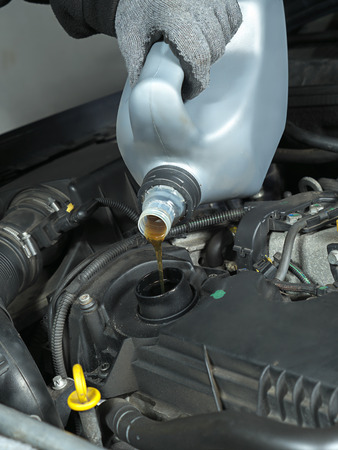 Auto mechanic replenishing engine oil の写真素材