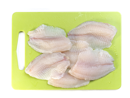 Tilapia fish fillets on green kitchen boardの写真素材