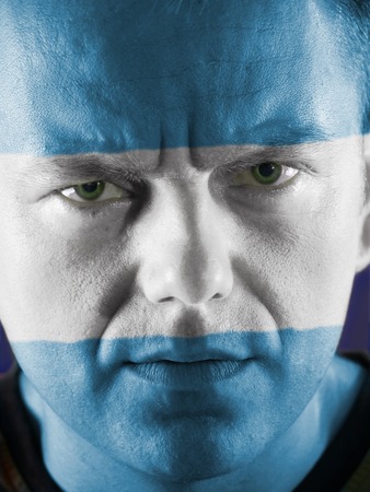 Closeup of young Argentinian supporter face painted with national flag colorsの写真素材