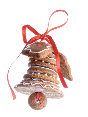 Christmas bell assembled from gingerbread shaped cookies and tied with red ribbon shot over white  backgroundの写真素材