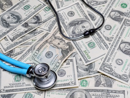 Stethoscope on pile of american dollar banknotesの写真素材