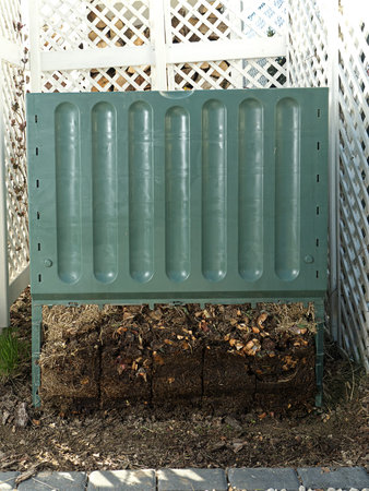 Green plastic compost bin with lower part removed to show advanced soil decomposition process