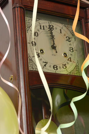 Wooden wall clock decorated with streamers and balloons indicating almost New Yearの写真素材
