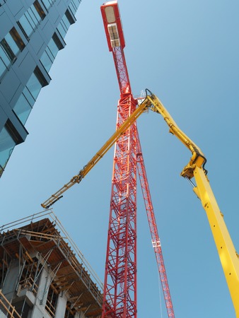 Highrise buildings under construction and two jib cranes over clear blue skyの写真素材