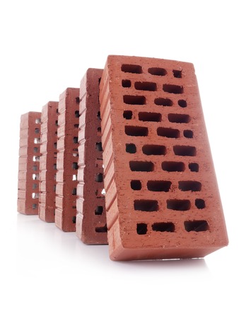 Line of red bricks with the first brick falling over the next one making a domino effect shot over whiteの写真素材