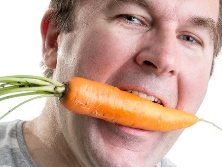 Man holding a fresh carrot in his mouthの写真素材