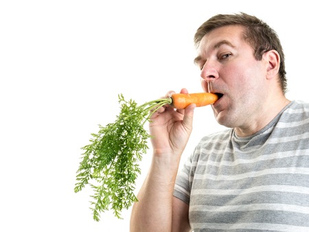 Man holding a fresh carrot in his mouthの写真素材