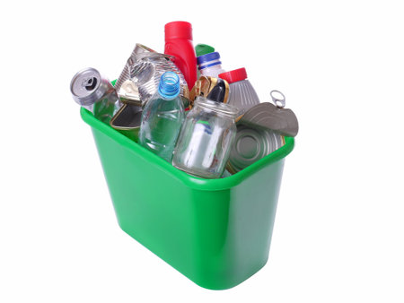 Green plastic trash bin filled with assorted domestic garbage - isolated on white backgroundの写真素材