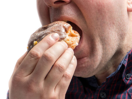 Side shot of man eating donut shot on whiteの写真素材