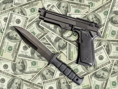 Knife and pistol placed on pile of american one hundred dollar billsの写真素材