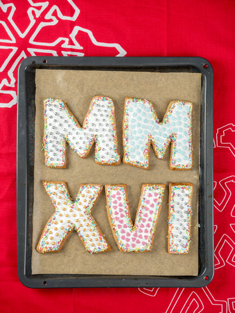 Home-made gingerbread cookies in shape of Roman numerals representing 2016 New Year date on baking trayの写真素材