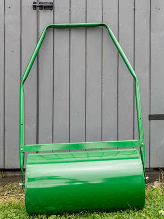 Lawn roller parked by grey wooden shedの写真素材