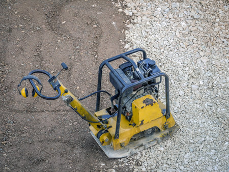 Old yellow plate compactor on aggregate bed