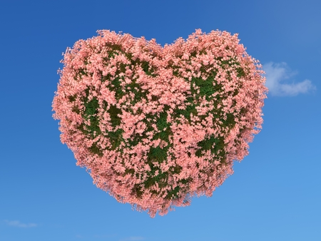 Heart shape covered with grass and pink flowers on blue skyの写真素材