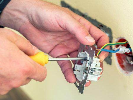 Closeup of electrician's hands installing wall socket