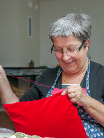 Older woman braiding red pillow case