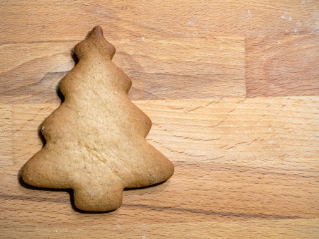 Christmas tree-shape metal cookie cutter casting shadow onto wooden board