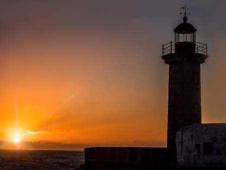 Silhouette of 19th century hexagonal lighthouse on the Douro River against the sunset, Porto, Portugalの写真素材