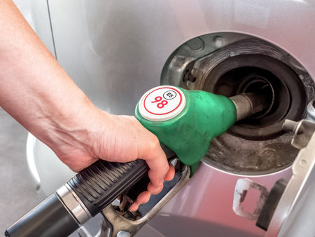 Closeup of female hand topping up car tank with unleaded 98 gasoline