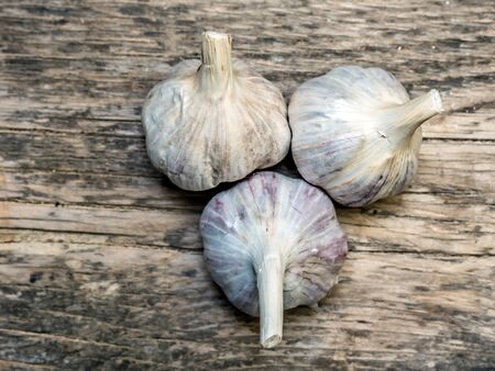 Three bulbs of garlic on wooden plank surfaceの写真素材
