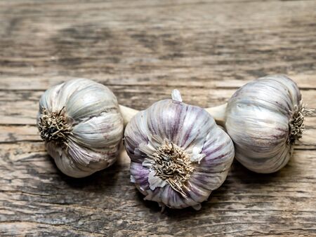 Three bulbs of garlic on wooden plank surfaceの写真素材
