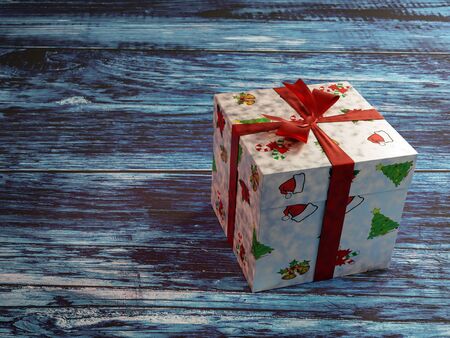 Christmas present box with red ribbon on rustic bluish wooden plank surfaceの写真素材