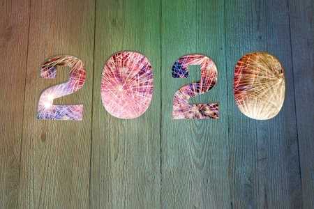 3D rendering of 2020 New Year date cut out in wooden fence with fireworks in the background