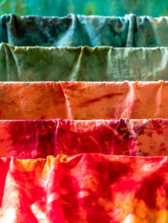Closeup of various colors hand-dyed wet cotton fabrics drying on a drierの写真素材