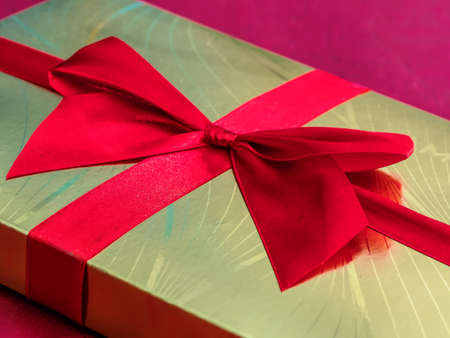 Closeup of golden chocolate box with red ribbonの写真素材