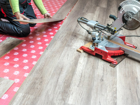 A carpenter laying new laminate panel floor in house apartmentの写真素材