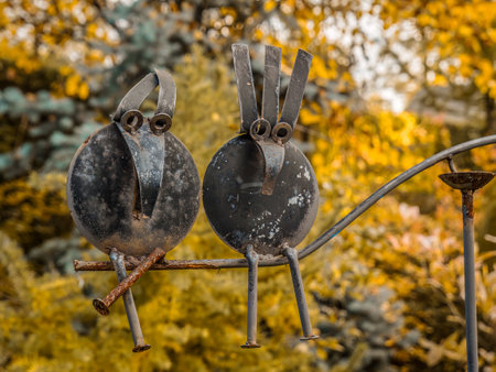 Metal garden decoration of two abstract bird figures perched on a branchの写真素材