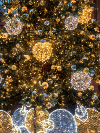 Elegant Christmas tree adorned with golden baubles, sparkling lights, and festive decorations. Captures the enchanting holiday atmosphere during a magical winter evening.の写真素材