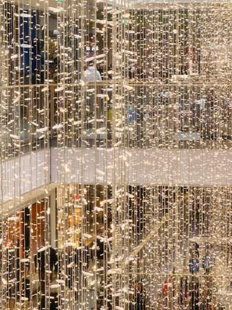 A bustling shopping mall adorned with holiday lights and decorations, filled with customers enjoying the festive ambiance while browsing the variety of retail storesの写真素材