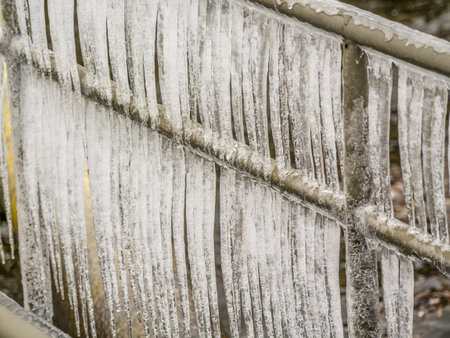 Icicles formed along a steel railing due to cold weather, symbolizing winter's harsh beauty.の写真素材