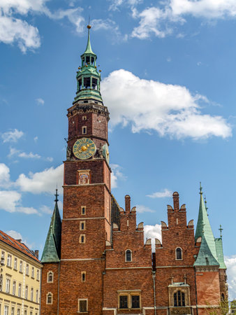 A vibrant scene featuring a historic Townhouse with clock tower surrounded by charming colorful buildings under a sunny, cloud-dotted blue sky, Wroclaw, Polandの写真素材