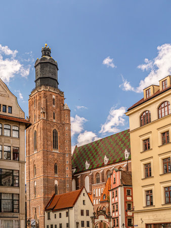 A striking view of a historic brick St. Elisabeth Church tower surrounded by vibrant rooftops and charming architecture under a bright, cloud-dotted blue skyの写真素材