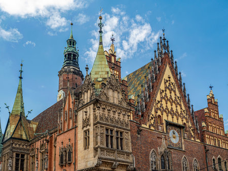 A striking view of a historic Gothic-style town hall featuring ornate details, towers, and a clock on a sunny day with clear blue skies, Wroclaw, Polandの写真素材