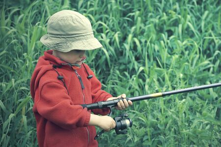 Little boy holding fishing rod  Grass at the backgroundの写真素材