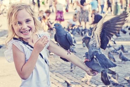 Smiling girl with pigeons on the arm in old town squareの写真素材