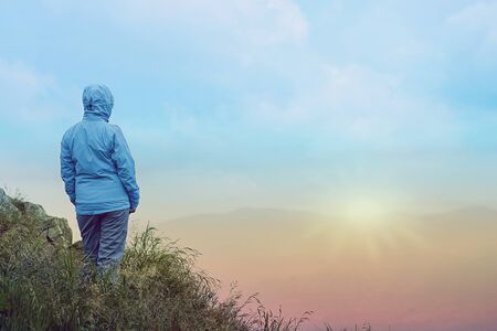 Woman standing over cliff at sunriseの写真素材