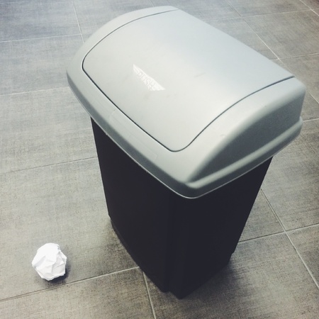 Crumpled piece of paper next to rubbish binの素材