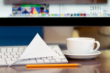 Paper airplane on the keyboard  PC display at backgroundの写真素材