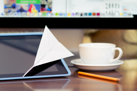 Paper airplane on the tablet  PC display and coffee cup at backgroundの写真素材
