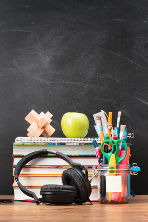 School accessories on desktop with blank blackboard in the backgroundの写真素材