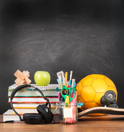 School accessories on desktop with blank blackboard in the backgroundの写真素材