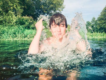 Boy splashing water on his faceの素材