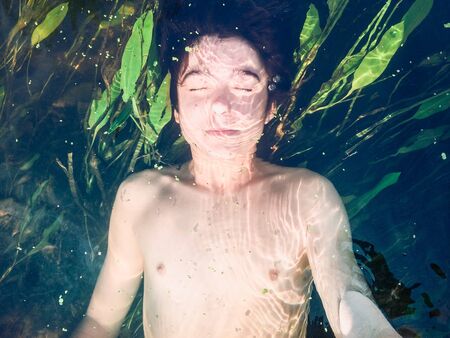 Boy submerged in a pure riverの素材