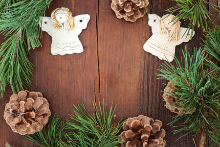 Earthen angels, pine twigs and cones decorations on wooden table. Space for textの写真素材
