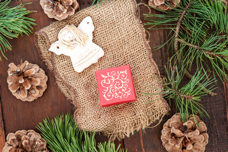 Christmas gift in small box, decorated with earthen angel and pine twigs and natural fabricの写真素材