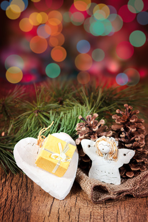 Christmas gift in small box, decorated with earthen heart, pine cones and twigs. Colourful blurred lights at backgroundの写真素材
